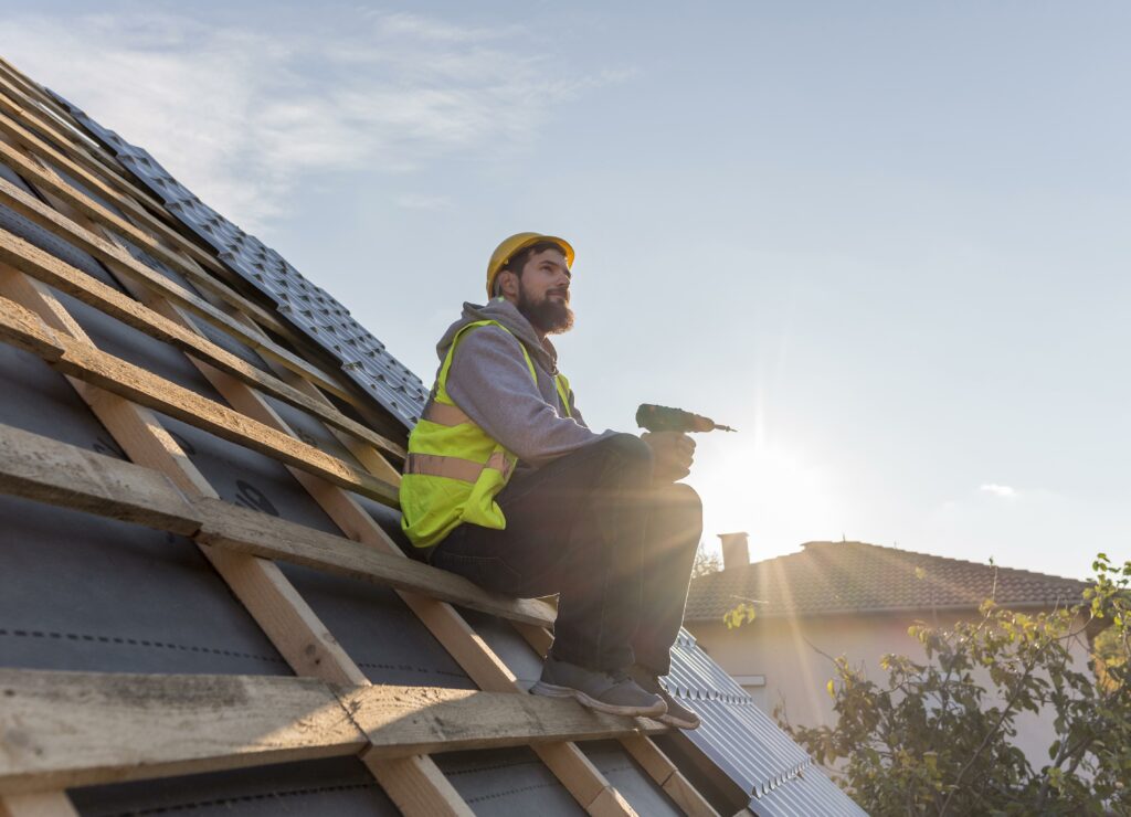 Our roofer sitting on the roof with a drill in his hand during the roofing installation